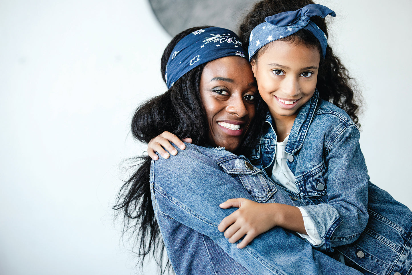 Mother and daughter wearing denim jackets and navy blue bandannas.