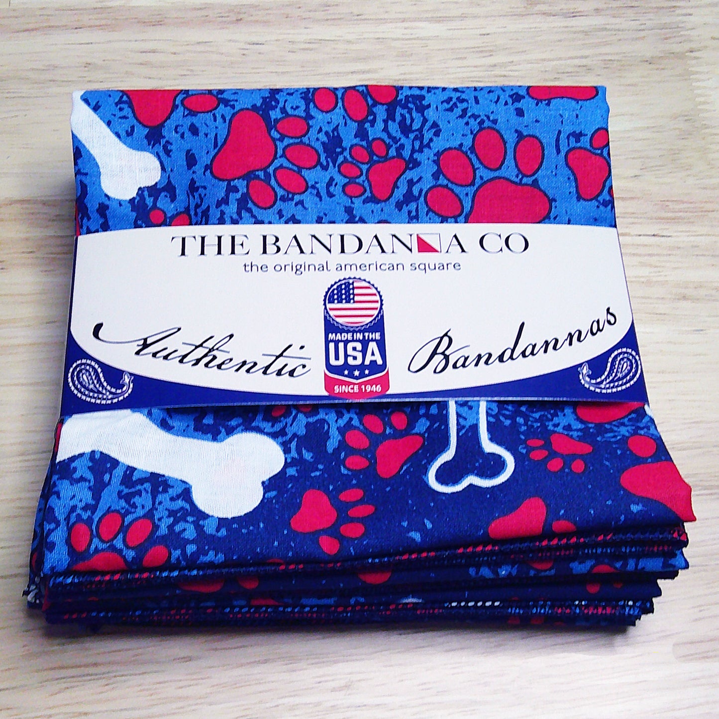 4-pack of Patriotic Bones Bandanna, 100% cotton, made in the USA with bone and paw print design, folded with label showing authenticity.